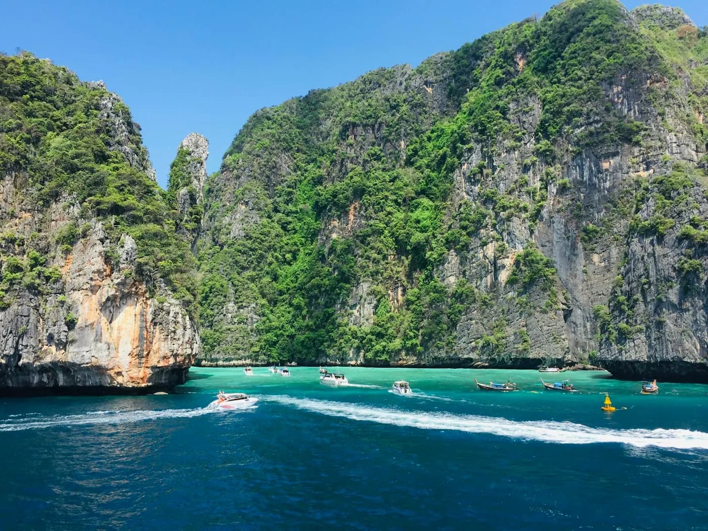 A boat threading between forested limestone islands
